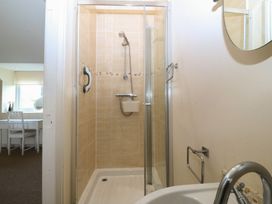 A shower enclosure with a shower head and sink at Llanallgo Church Rooms 