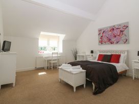 A bedroom with a bed, desk, and television at Llanallgo Church Rooms