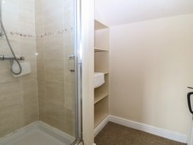 A bathroom with a shower and shelves at Llanallgo Church Rooms