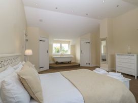 A bedroom with a bathtub and dresser at Llanallgo Church Rooms