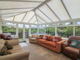 A conservatory with seating and windows at Llanallgo Church Rooms in 