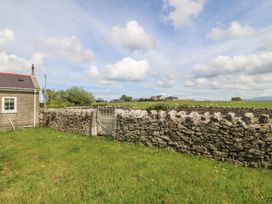 An outdoor view showing a house and a stone wall with a gate in Llanallgo Church Rooms 
