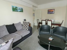 A living room with a sofa and dining area at Sea Breeze Rhos-on-Sea