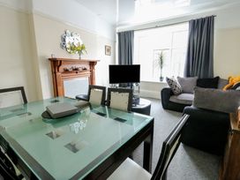 A living room with a dining table and television at Sea Breeze in Rhos-on-Sea