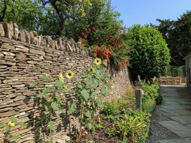 A garden with sunflowers and stone wall at Easter Cottage in Burford