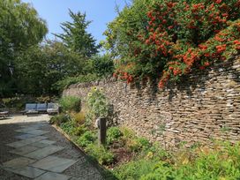A garden with a stone wall and seating area at Easter Cottage in Burford