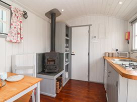 A kitchen with a wood stove and sink at The Shepherds Hut in Chippenham