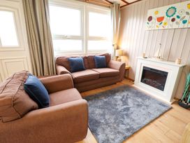 A living room with a sofa and fireplace at Moggs Retreat in Chapel St Leonards