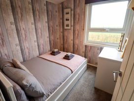 A bedroom with a bed and towels folded on top at Moggs Retreat in Chapel St Leonards