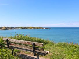 A bench overlooking the ocean and hills at Happy Daze in Morfa Nefyn
