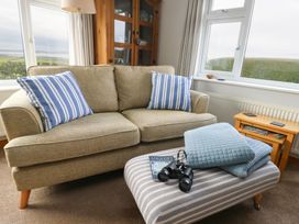 A living room with a sofa, coffee table, and binoculars at Yr Orsedd, Llanfaethlu