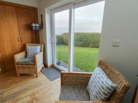 A sunroom with two armchairs and a sliding door at Yr Orsedd in Llanfaethlu
