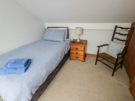 A bedroom with a bed and a chair at Yr Orsedd in Llanfaethlu