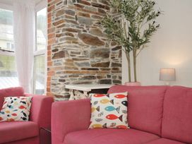 A living room with a pink sofa and cushions at Stargazy in Trebarwith Strand near Tintagel