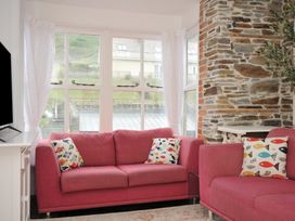 A living room with pink sofas and a television at Stargazy in Trebarwith Strand near Tintagel