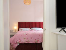 A bedroom with a red bed and bedside lamp at Stargazy, Trebarwith Strand near Tintagel