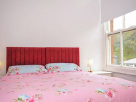 A bedroom with a red headboard and a window at Stargazy near Trebarwith Strand