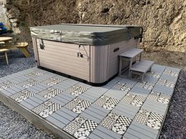 A hot tub with steps on a tiled patio in an outdoor area at The Cottage in Llaniestyn
