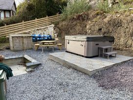 An outdoor area with a hot tub, picnic table, and storage shed at The Cottage in Llaniestyn