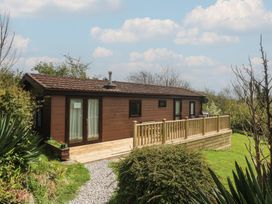 A cabin with a deck and landscaping at Castell Chalet in Penrhos near Pwllheli