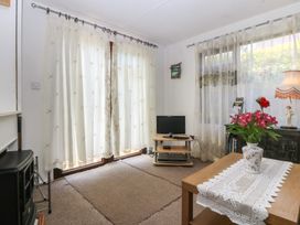 A living room with curtains and a television at Castell Chalet in Penrhos near Pwllheli