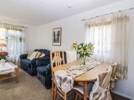 A living room with a sofa and dining table at Castell Chalet Penrhos near Pwllheli