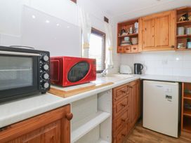 A kitchen with appliances and cabinets at Castell Chalet in Penrhos near Pwllheli