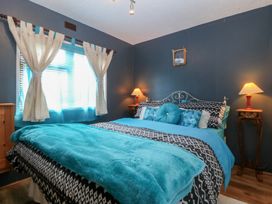 A bedroom with a bed and bedside tables with lamps at Castell Chalet Penrhos near Pwllheli