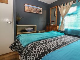 A bedroom with a bed, shelves, and window at Castell Chalet in Penrhos near Pwllheli