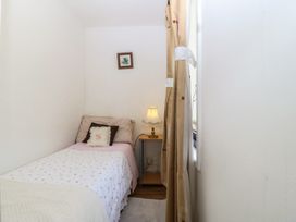 A bedroom with a bed and a lamp at Castell Chalet in Penrhos near Pwllheli