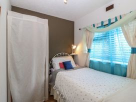 A bedroom with a bed, lamp, and window at Castell Chalet in Penrhos near Pwllheli