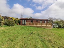A chalet with decking and lawn at Castell Chalet in Penrhos near Pwllheli