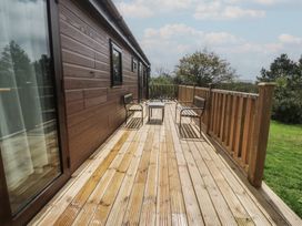 An outdoor wooden deck with chairs and a table at Castell Chalet Penrhos near Pwllheli