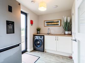A laundry room with a refrigerator and washing machine at Cowslip in Bamburgh