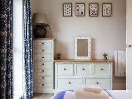 A bedroom with a dresser and mirror at Cowslip in Bamburgh