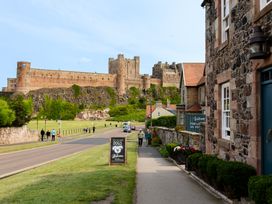 A view of a castle from a path with people walking at Cowslip in Bamburgh
