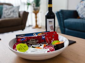 A plate with snacks and a bottle of wine in a living room at Betony in Bamburgh