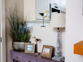 A living room with plant, lamp and photo frames at Betony in Bamburgh