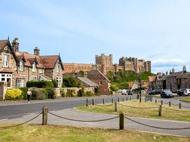 A street view showcasing houses and a castle at Betony in Bamburgh
