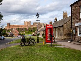 A street with a castle view, telephone box, bicycle and bench at Betony in Bamburgh