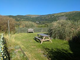 A garden with a bench and table at Minydon in Fairbourne
