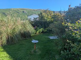 A garden with grass and a bird bath at Minydon in Fairbourne