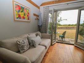 A living room with a sofa and open door leading to outdoor seating at The Lodge at Mortons in Hankerton