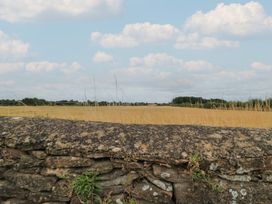 A field with a stone wall and clouds at The Lodge at Mortons Hankerton