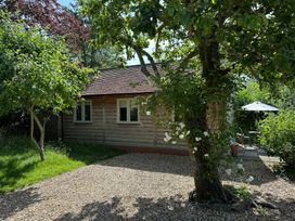 A cottage with trees and a patio area at The Lodge at Mortons in Hankerton
