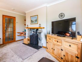 A living room with a stove and television at Pen Y Garth in Mynytho near Llanbedrog