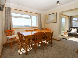 A dining room with a wooden table and chairs at Pen Y Garth in Mynytho near Llanbedrog