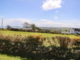A view of grass and sea with houses in the background at Pen Y Garth in Mynytho near Llanbedrog