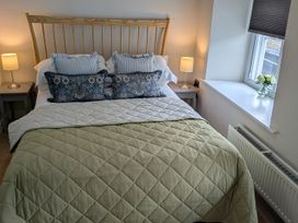 A bedroom with a bed, lamp, and flowers at Troopers Cottage in Frome