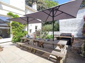 An outdoor seating area with a table and umbrellas at Holcombe House in Torquay